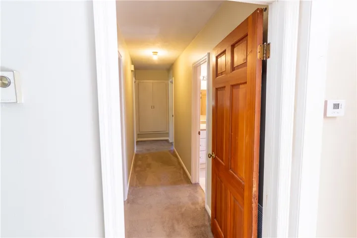 An inviting hallway connects the living spaces with carpeted flooring and classic wood doors.