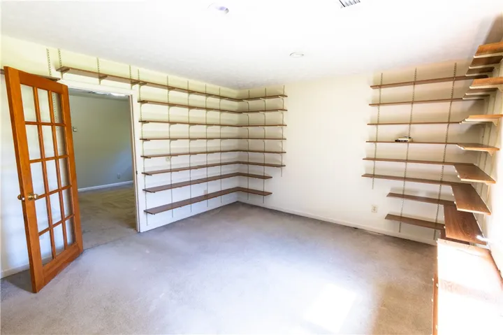 Ample wall-mounted shelving and a classic glass-paned door highlight this versatile room.