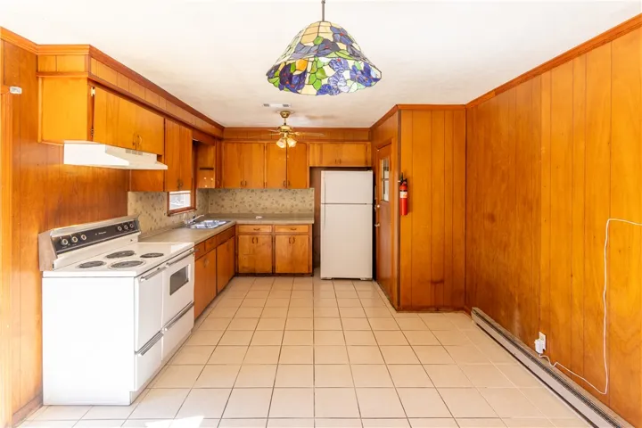 Rich wood paneling and classic tile flooring create a warm atmosphere in this functional kitchen.