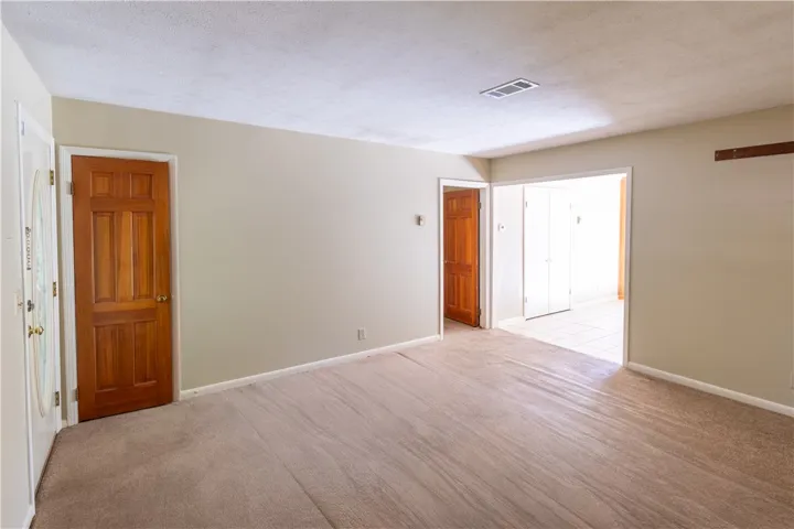 Warm wood doors and clean lines define this versatile living space featuring neutral carpeting.