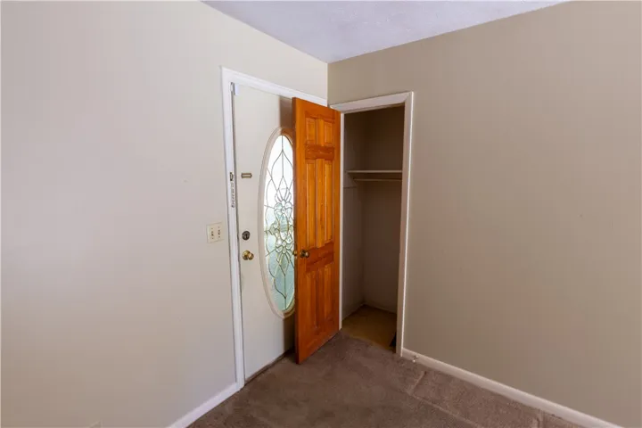 An inviting entryway features a decorative glass front door, carpet flooring, and a convenient closet.