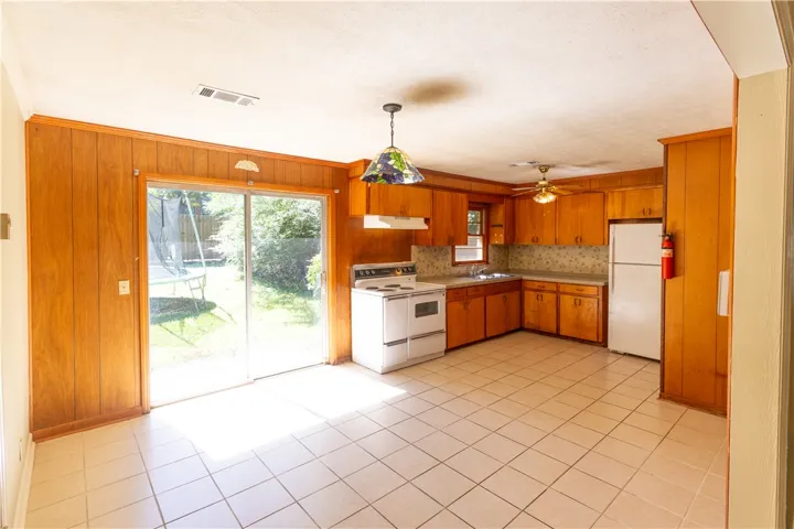 Rich wood paneling paired with tiled flooring defines this classic kitchen and dining area.