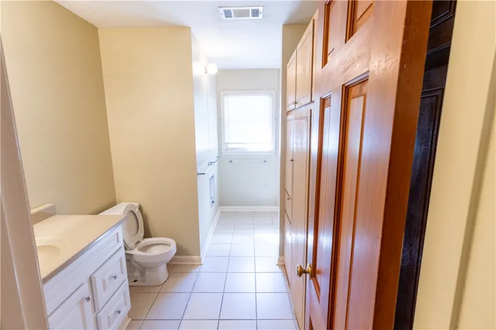Tiled flooring and built-in wooden cabinetry define this functional bathroom layout.