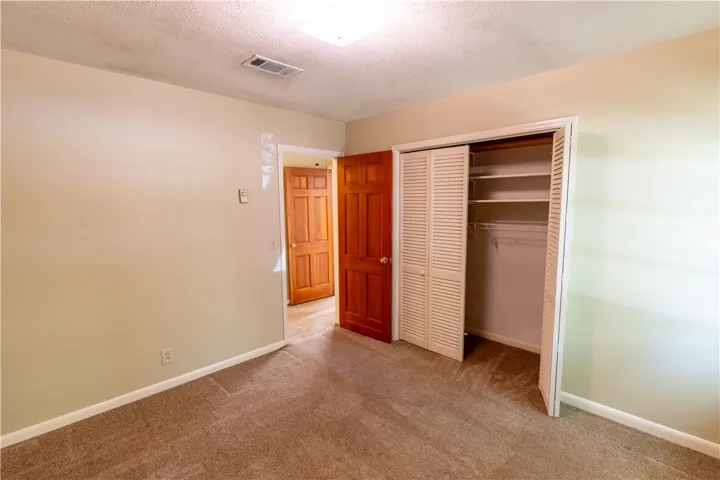 A classic bedroom features comfortable carpeting and a spacious built-in closet with louvered doors.