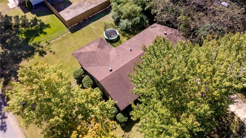Mature trees surround a single-family home with a fenced backyard.