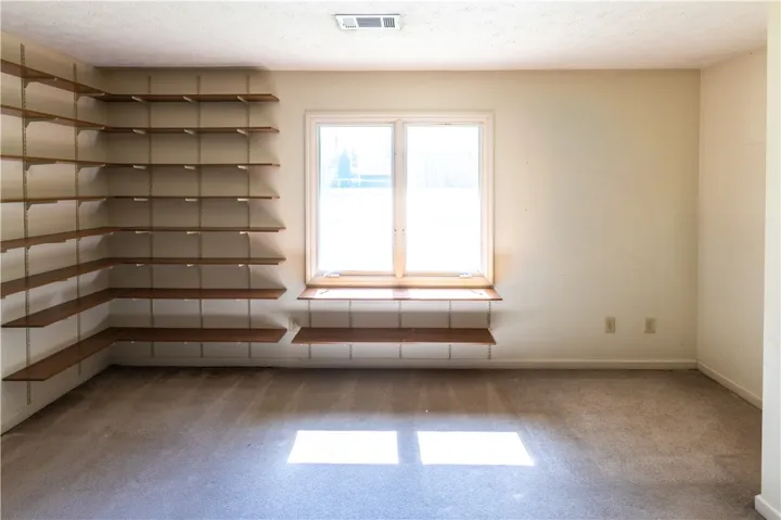 Ample built-in shelving and soft carpeting define this versatile bonus space with natural light.