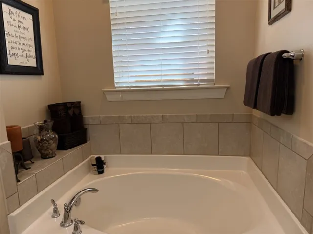 Tiled accents surround a deep soaking tub situated beneath a classic multi-paned window.