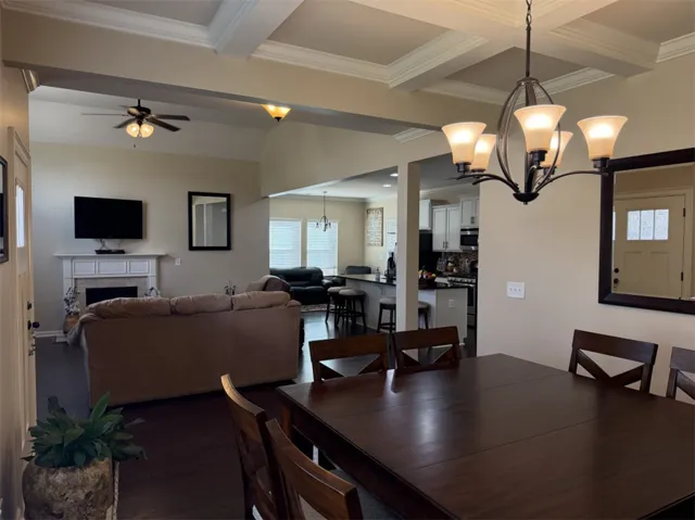 An open floor plan connects the dining area to the living space under elegant coffered ceilings.