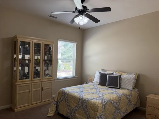 A quiet bedroom retreat highlights a large window and textured carpeting.
