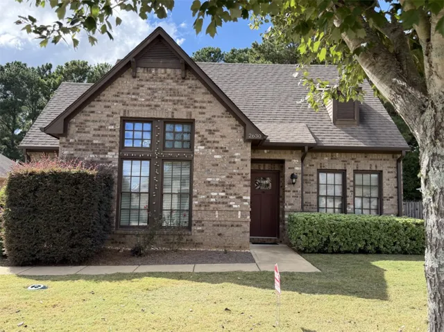 Classic brick exterior elements harmonize with steep rooflines and tidy landscaping on this charming facade.