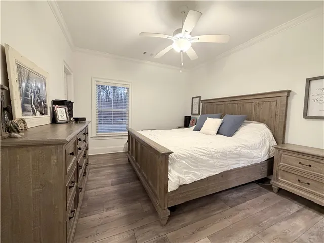 Crown molding and wide-plank wood-style floors elevate this comfortable sleeping space.