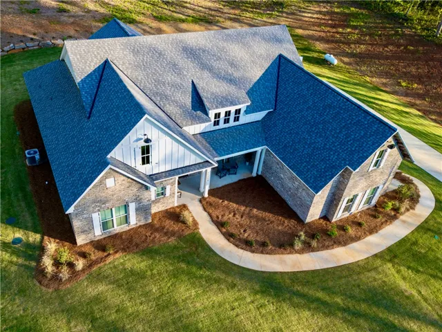An aerial perspective showcases the classic brick and board-and-batten exterior under a multi-gabled roofline.