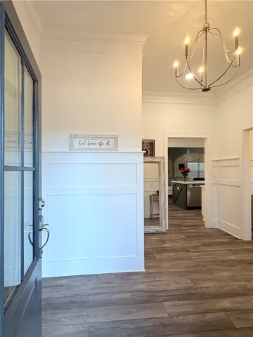 An inviting entryway showcases clean wainscoting, high ceilings, and classic wood-look flooring.