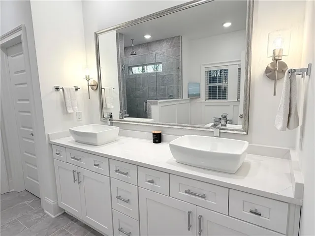 A spacious double vanity features sleek vessel sinks, stone countertops, and classic tile flooring.