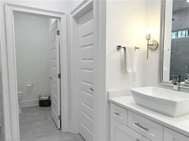 Crisp trim moldings frame this sleek modern washroom space with classic stone counters.