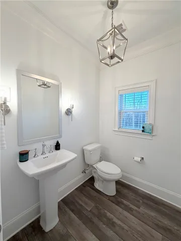 Rich wood-look flooring and crisp crown molding elevate this charming powder room.