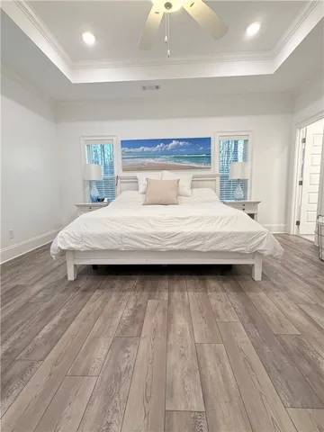 Rich wood-plank flooring complements a deep tray ceiling with classic molding detail.