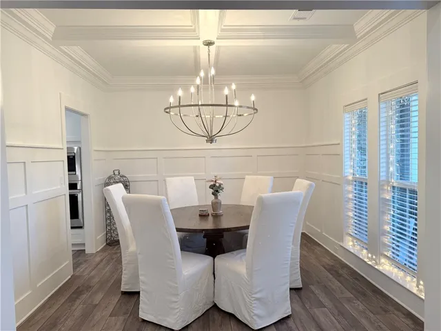 An elegant dining space showcases refined board and batten walls underneath a classic coffered ceiling.