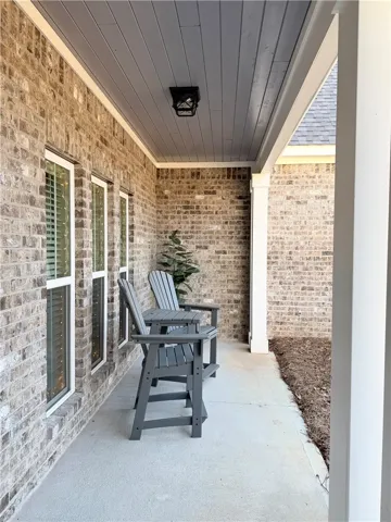 A covered concrete porch showcases textured brick siding and a painted wood-paneled ceiling.