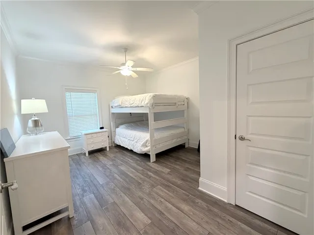 Gleaming wood-look floors and detailed crown molding elevate this serene sleeping space.