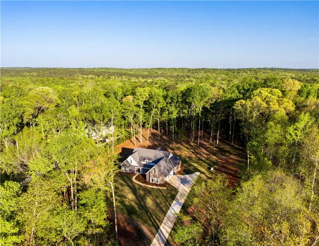 A private driveway winds toward this secluded residence enveloped by a dense canopy of mature trees.