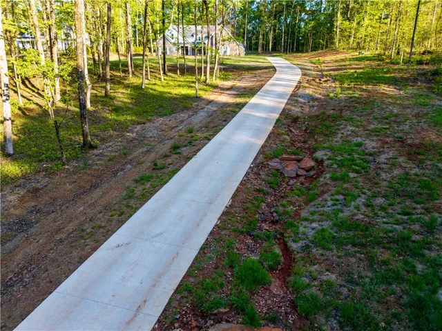 A long paved driveway winds through mature trees toward the home nestled in a clearing.