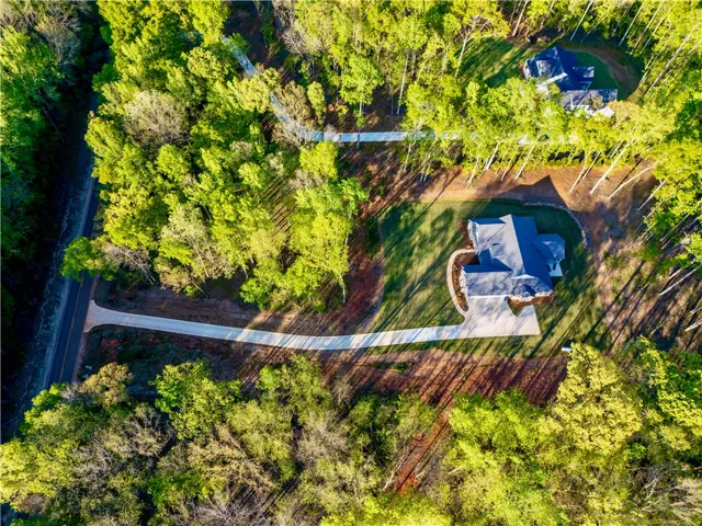 A secluded wooded estate features a private paved drive leading through dense mature trees.