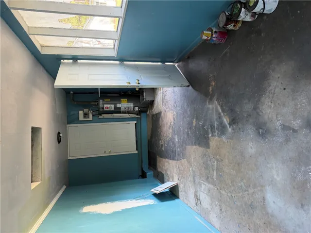 An utility space showcases durable concrete flooring, structured walls, and an overhead window panel.