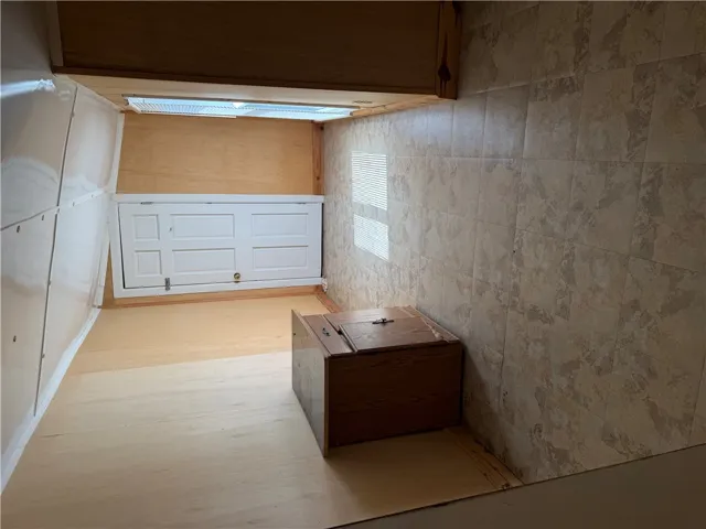 Natural light streams through a skylight onto clean wood flooring and tiled wall finishes.