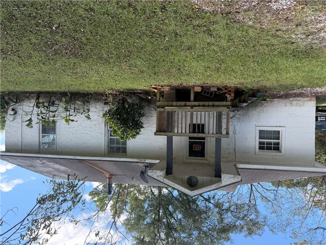 A classic block exterior features a raised entry porch framed by mature green surroundings.