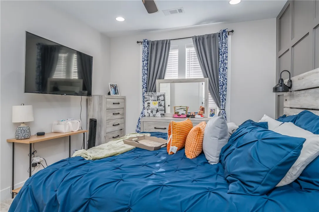 Crisp recessed lighting illuminates a spacious bedroom complete with a detailed wood-paneled accent wall.