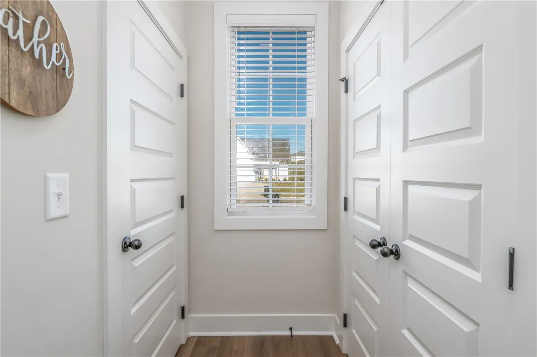 A well-positioned window bathes the hallway in natural light, showcasing rich wood floors and clean trim.