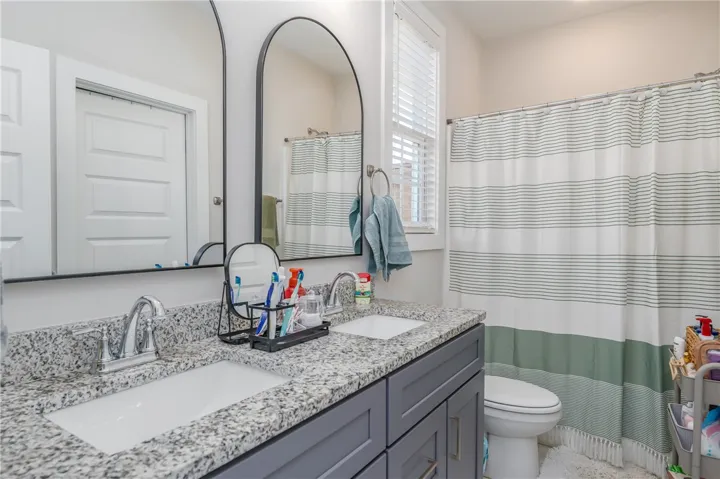 Polished granite counters and a dual vanity define this clean, modern bathroom space.