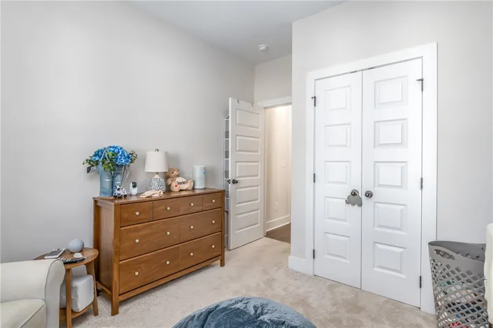 Plush carpeting anchors this versatile secondary bedroom featuring tall paneled closet doors.