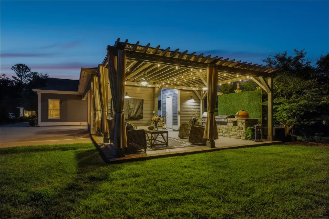An inviting outdoor kitchen with 3 grilling stations is located on the expansive rear patio. A beautifully crafted pergola provides coverage and includes 2 ceiling fans.