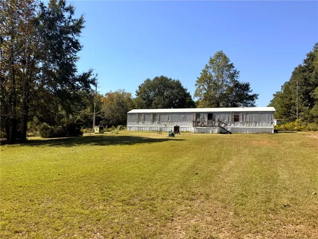 Mature trees frame a spacious grassy lawn leading up to the main structure.