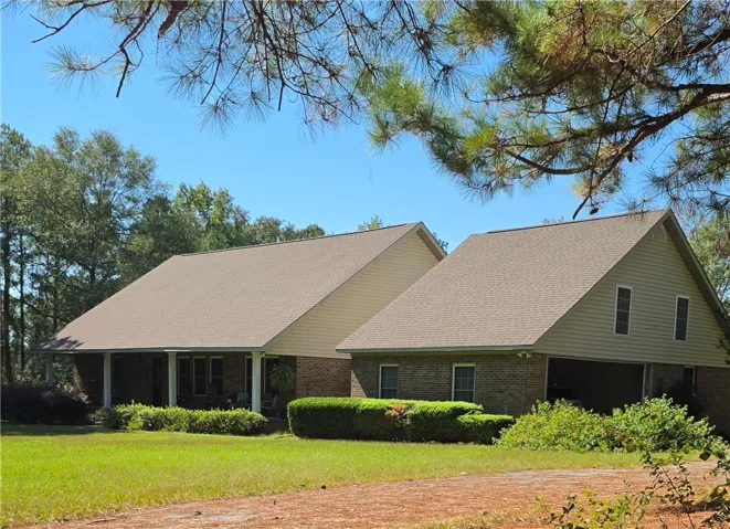 A classic brick facade is framed by mature trees and a manicured green lawn.