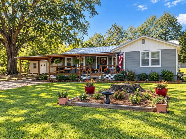 A classic front porch spans the length of this charming ranch-style home set amidst mature trees.