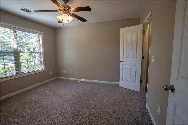 A classic bedroom features comfortable carpeting and a large window looking out to the yard.