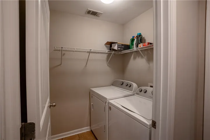 A dedicated laundry space features overhead wire shelving and durable tile flooring.