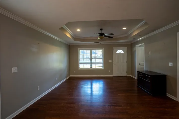 Rich hardwood flooring complements a striking tray ceiling and clean crown molding details.