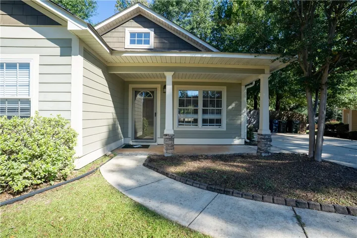 A curved concrete walkway leads to a welcoming covered front porch framed by classic columns.