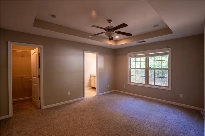 An elegant tray ceiling centers this comfortable bedroom with soft carpeting and natural light.