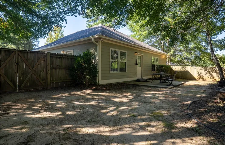 Mature trees shade a private backyard complete with a concrete patio and full wooden fencing.