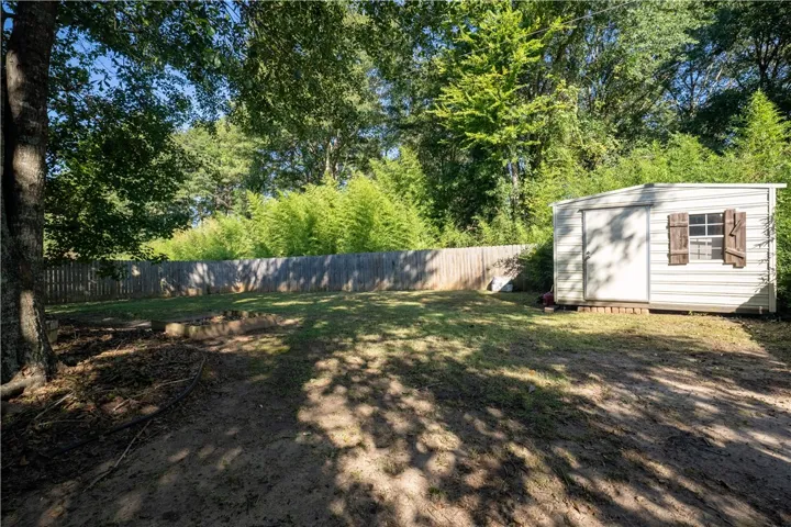 Mature trees shade a spacious backyard secured by wood privacy fencing.