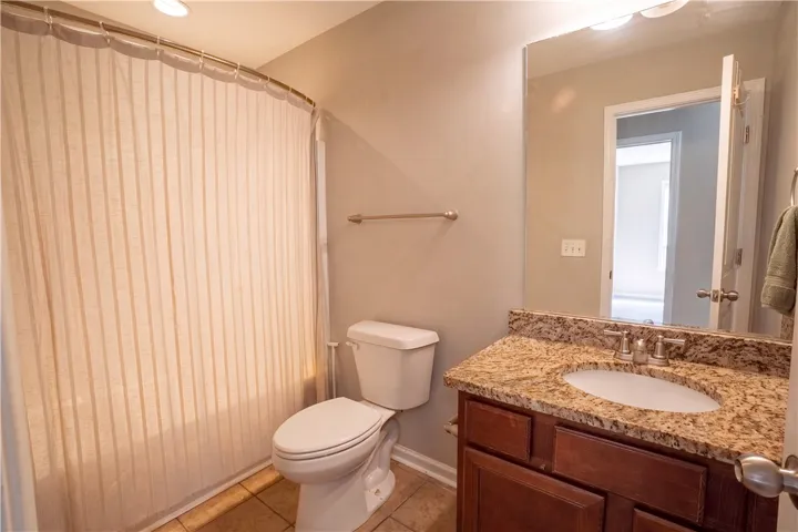 Polished stone counters and rich cabinetry elevate this functional full bathroom.