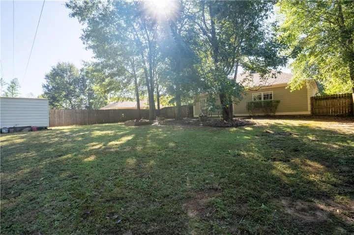Mature trees shade a spacious, fully fenced yard behind the home.