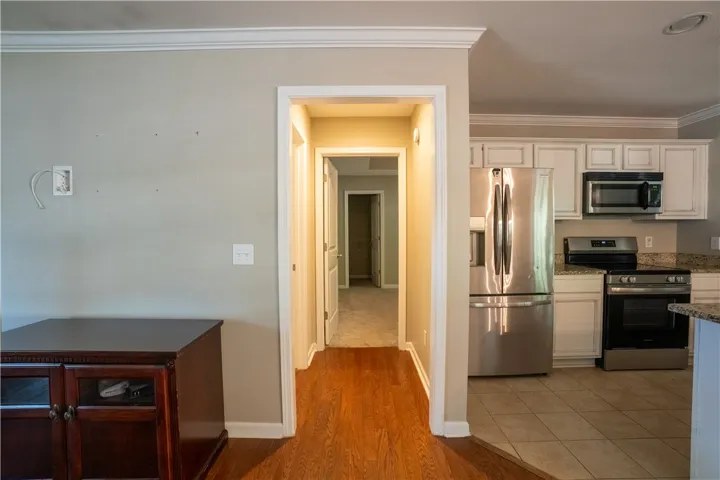 Transition seamlessly from the warm wood-floored entryway into the adjacent kitchen and hallways.