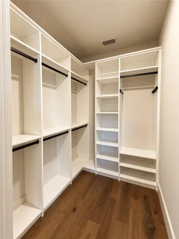 Custom built-in shelving and rich wood flooring optimize storage space in this closet.