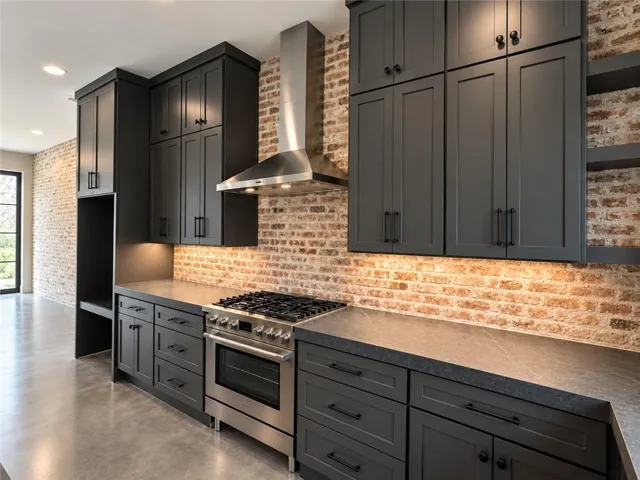 Exposed brick walls and sleek dark cabinetry define this modern industrial culinary space.